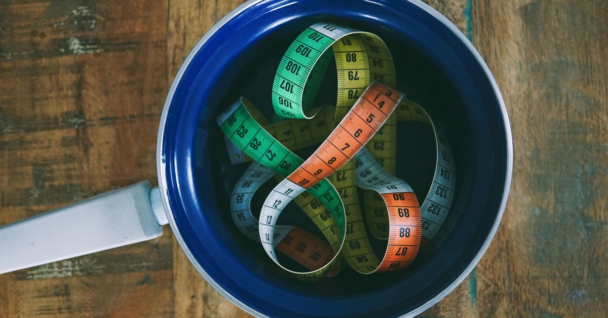 Top view of colorful measuring tapes in a ceramic pan placed on a rustic wooden table.